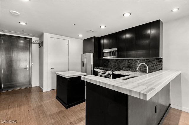 kitchen with visible vents, a kitchen island, appliances with stainless steel finishes, light countertops, and dark cabinets