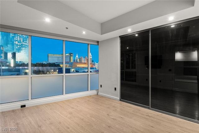 empty room with a view of city, recessed lighting, and wood finished floors