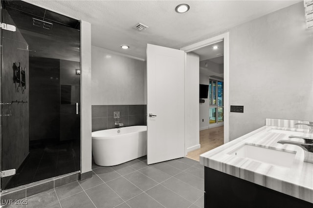 bathroom featuring visible vents, a freestanding tub, a sink, tile patterned flooring, and a shower stall