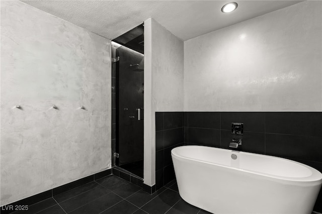 full bath featuring tile patterned floors, a freestanding tub, and a stall shower