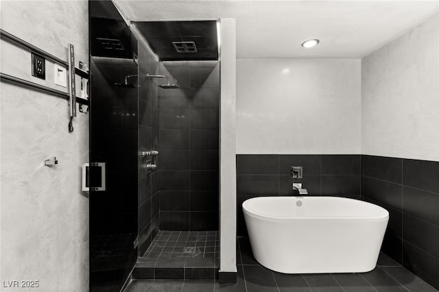 bathroom featuring tile patterned floors, a shower stall, a freestanding bath, and tile walls