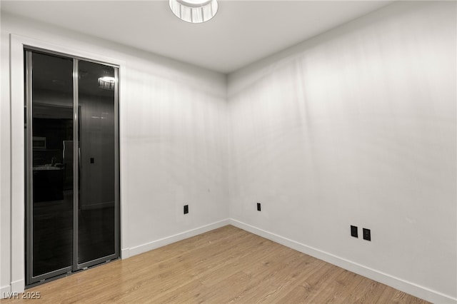 empty room featuring baseboards and light wood finished floors