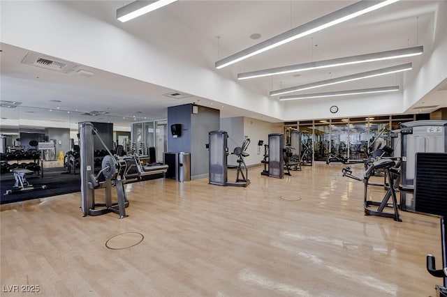 workout area featuring visible vents, a towering ceiling, and wood finished floors