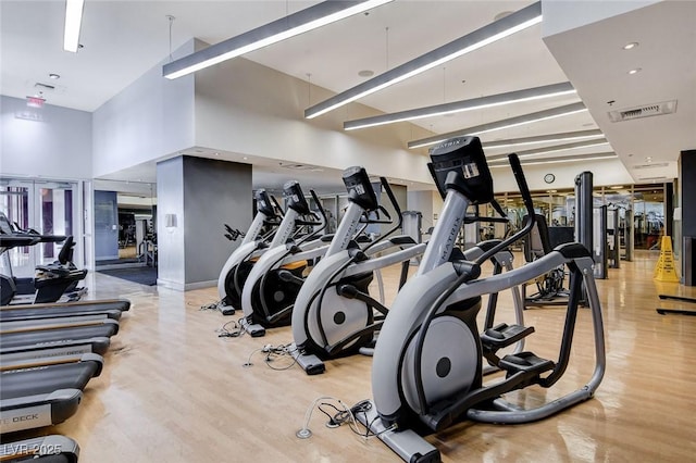 gym featuring visible vents, wood finished floors, and a towering ceiling