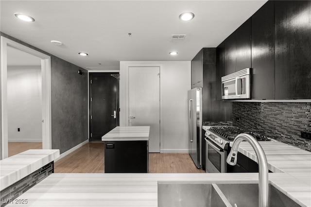 kitchen featuring visible vents, appliances with stainless steel finishes, light wood-style floors, and dark cabinets