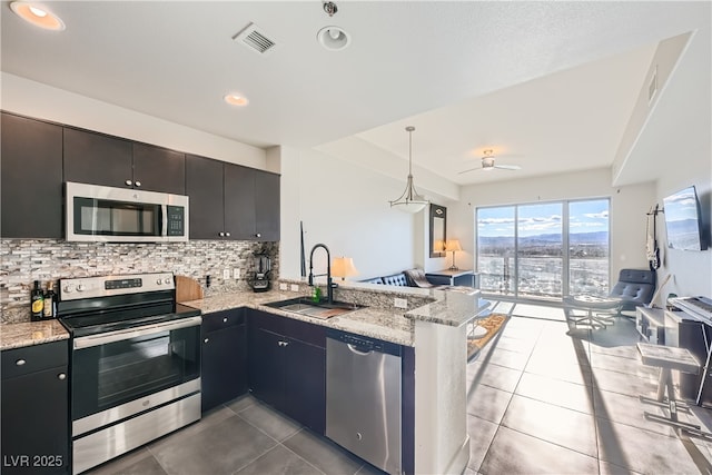 kitchen with tasteful backsplash, visible vents, a peninsula, stainless steel appliances, and a sink