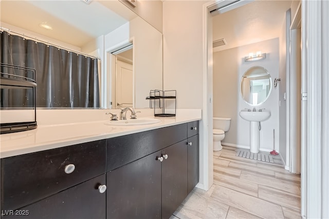 bathroom with a sink, visible vents, baseboards, and toilet