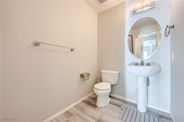 bathroom with a sink, baseboards, toilet, and wood finished floors