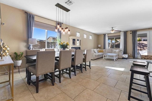 dining room featuring ceiling fan with notable chandelier, a healthy amount of sunlight, visible vents, and baseboards