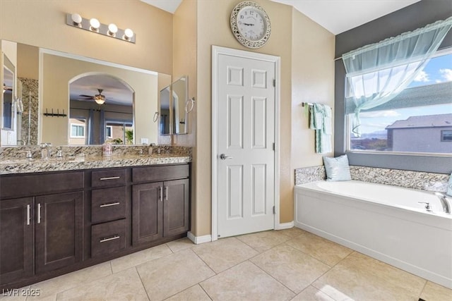 full bath featuring double vanity, a bath, ceiling fan, and tile patterned flooring