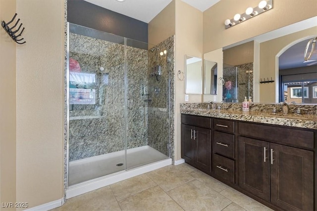 bathroom featuring tile patterned floors, a sink, a shower stall, and double vanity