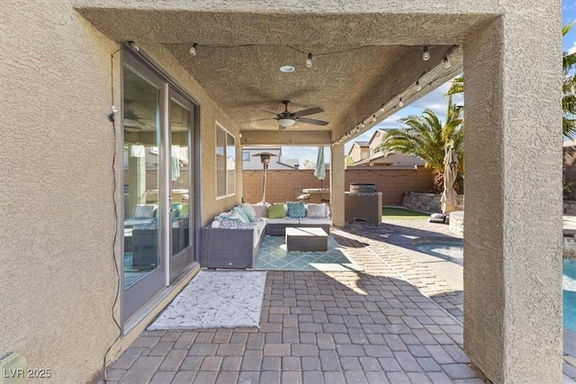 view of patio with an outdoor living space, ceiling fan, and fence