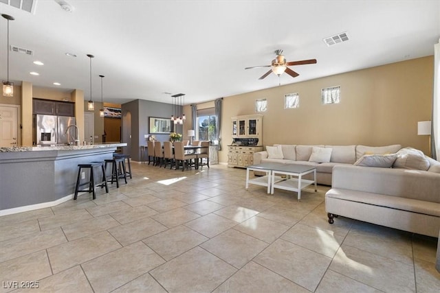 living room with light tile patterned floors, visible vents, and ceiling fan