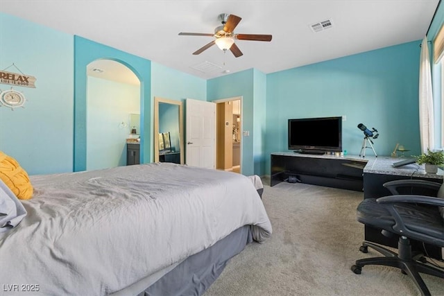 carpeted bedroom featuring arched walkways, visible vents, ensuite bath, and a ceiling fan