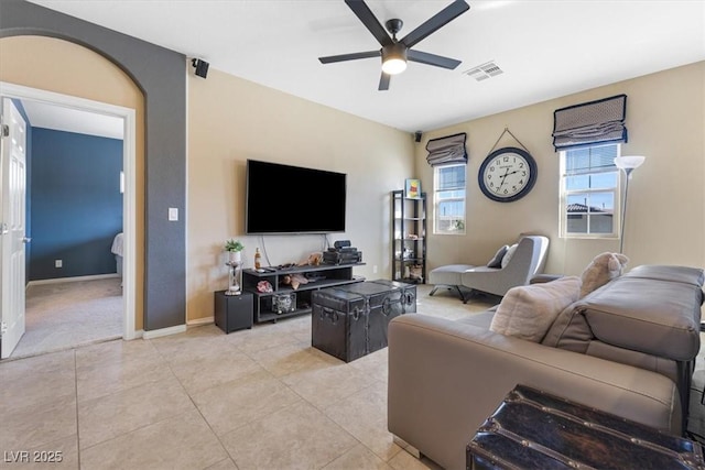 living area featuring light tile patterned floors, visible vents, baseboards, and a ceiling fan