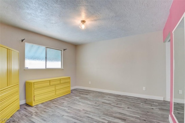 unfurnished bedroom featuring a textured ceiling, baseboards, and light wood-style floors