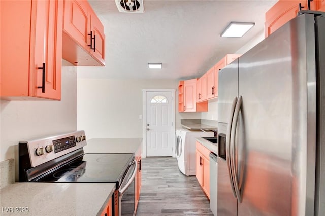 kitchen with visible vents, light wood-type flooring, light countertops, washer / dryer, and appliances with stainless steel finishes