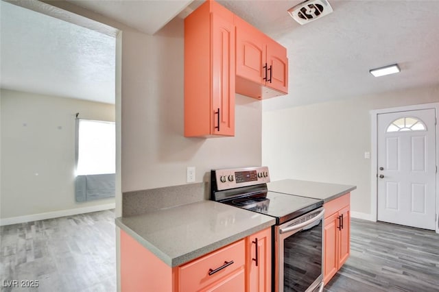 kitchen featuring baseboards, a textured ceiling, stainless steel electric range oven, and light wood-style floors