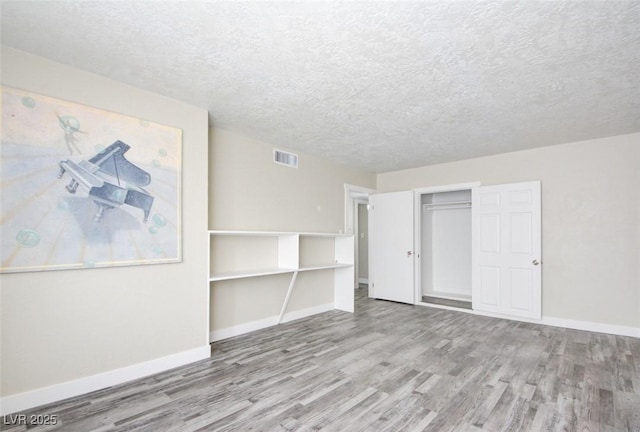 interior space featuring wood finished floors, visible vents, a closet, and baseboards