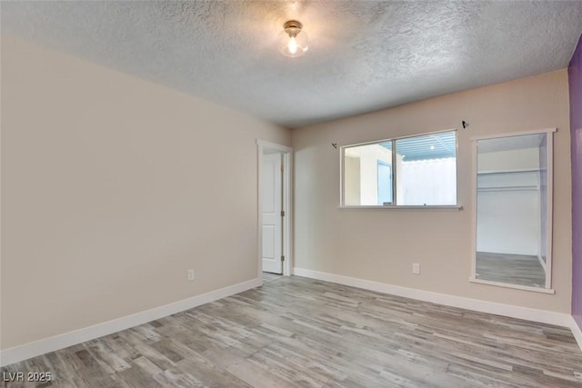 spare room with baseboards, a textured ceiling, and wood finished floors