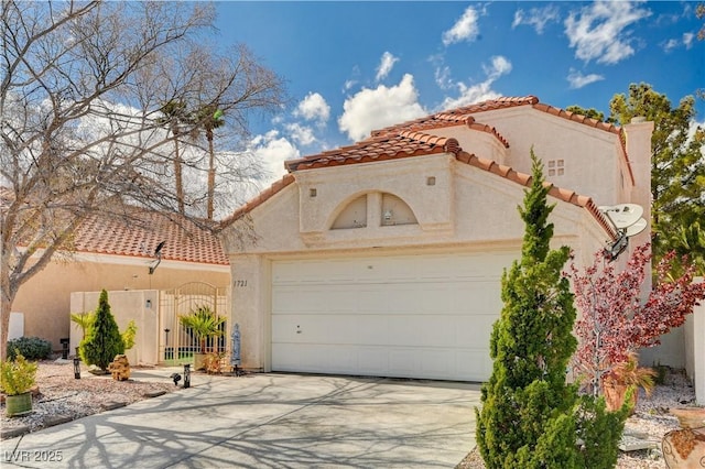 mediterranean / spanish home with a gate, driveway, an attached garage, stucco siding, and a tiled roof