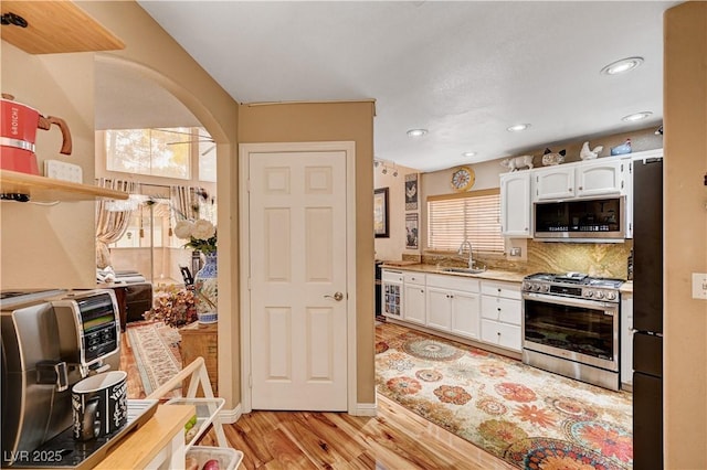 kitchen featuring light wood-style flooring, appliances with stainless steel finishes, white cabinetry, and a sink