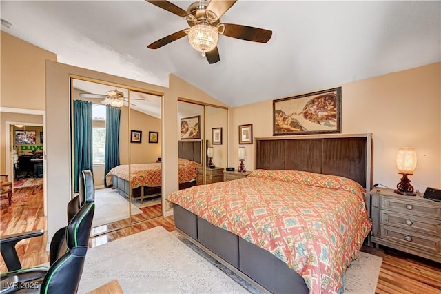 bedroom featuring vaulted ceiling, multiple closets, light wood-type flooring, and ceiling fan