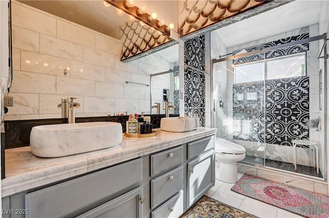 bathroom with double vanity, toilet, a stall shower, and a sink