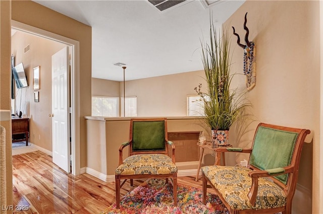 living area with visible vents, attic access, baseboards, and wood finished floors