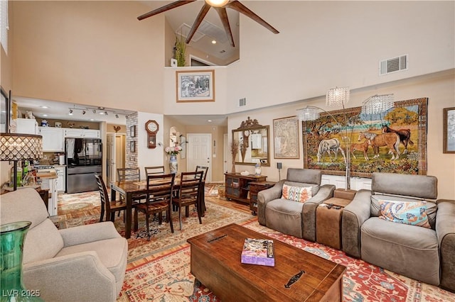 living room featuring visible vents, a high ceiling, and ceiling fan