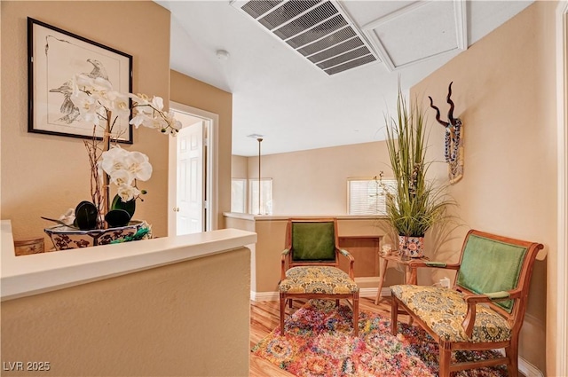 living area with wood finished floors, visible vents, and baseboards