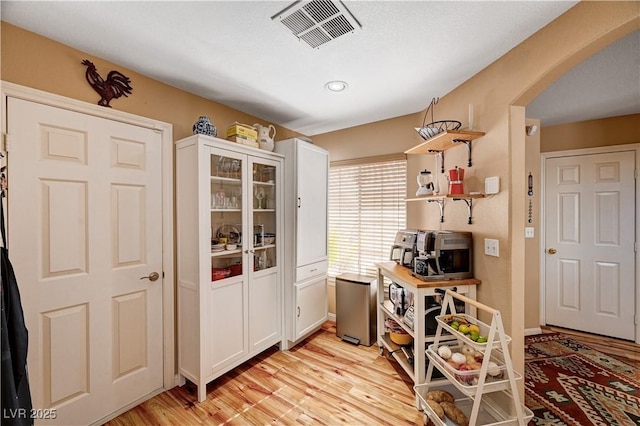 office featuring visible vents, arched walkways, baseboards, and light wood finished floors