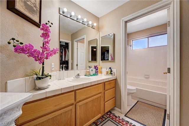 bathroom featuring a textured wall, toilet, vanity, and tile patterned flooring