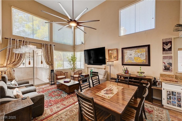 living room featuring wood finished floors, a towering ceiling, and a ceiling fan