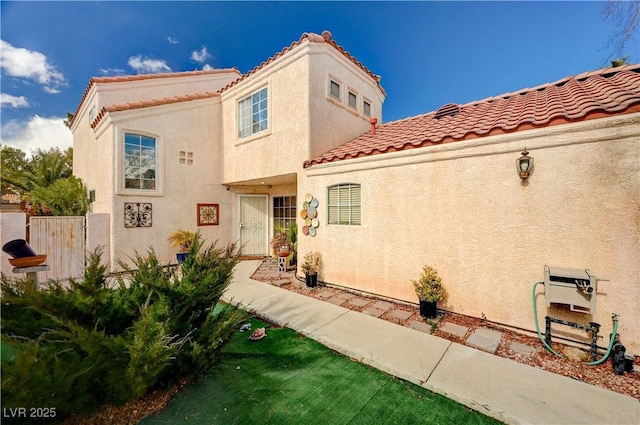 view of front facade featuring a tiled roof, fence, and stucco siding