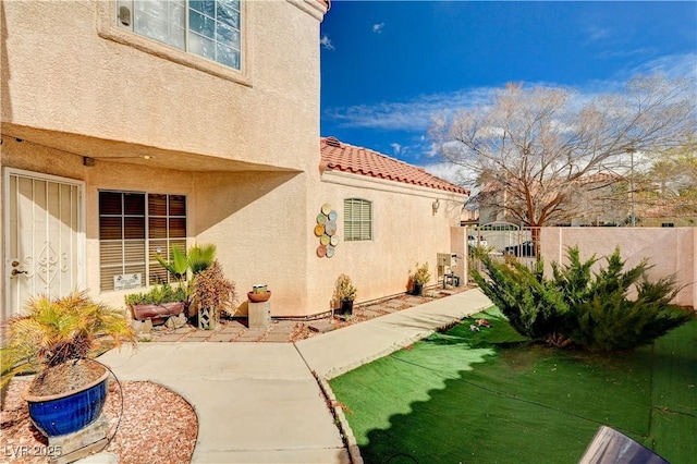 view of home's exterior with a patio area, stucco siding, a lawn, and fence