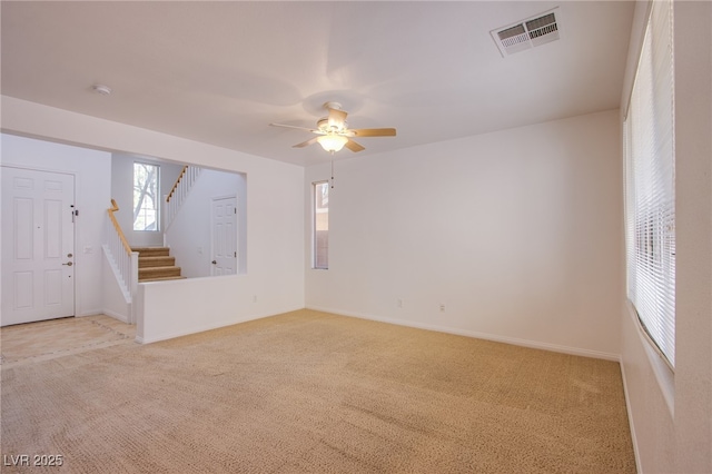 unfurnished room featuring stairway, light colored carpet, visible vents, and baseboards