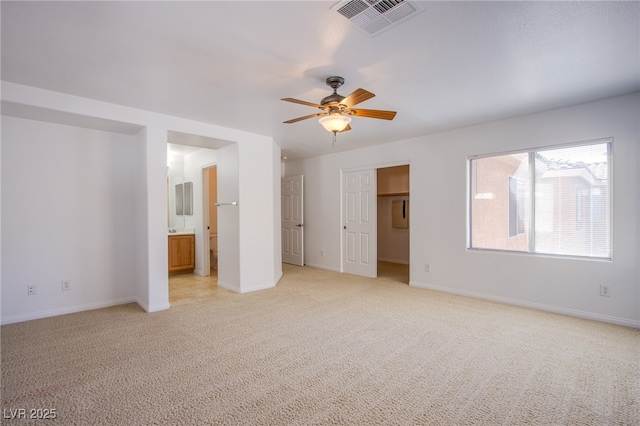 unfurnished bedroom featuring a ceiling fan, visible vents, baseboards, ensuite bath, and light colored carpet