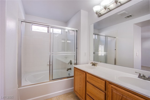 bathroom featuring tile patterned flooring, visible vents, bath / shower combo with glass door, and a sink