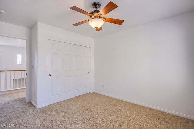 unfurnished bedroom with a closet, light colored carpet, and baseboards