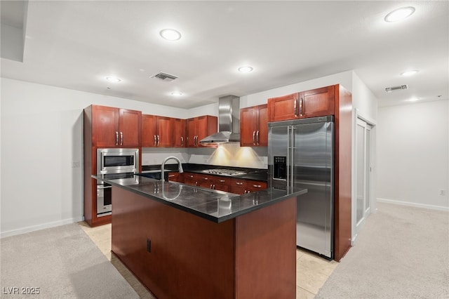 kitchen featuring visible vents, stainless steel appliances, dark countertops, wall chimney range hood, and light colored carpet