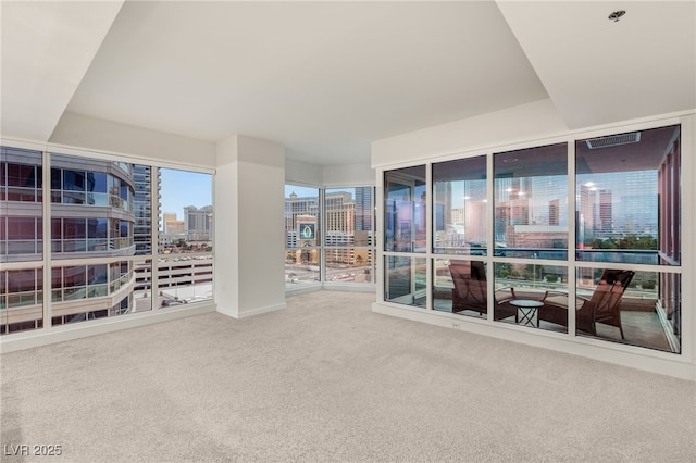 unfurnished room featuring a city view and carpet floors