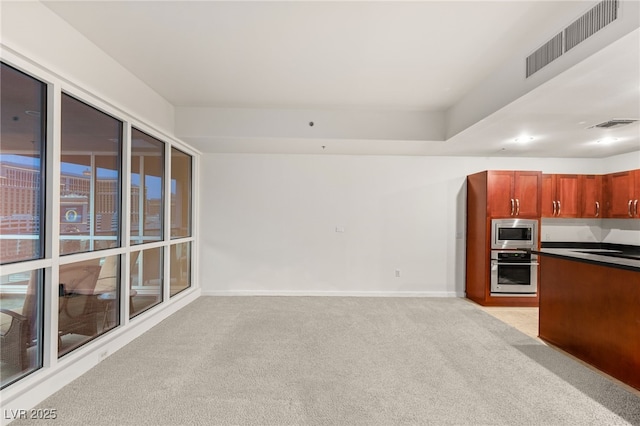 kitchen featuring dark countertops, visible vents, baseboards, light carpet, and stainless steel appliances