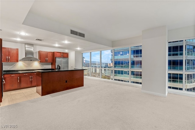 kitchen with visible vents, built in refrigerator, light carpet, and wall chimney exhaust hood