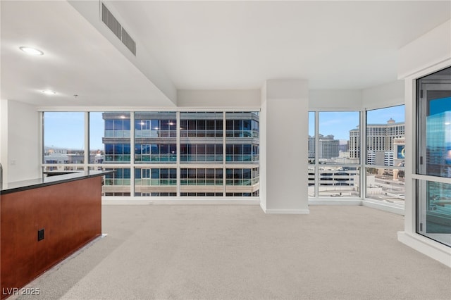 carpeted empty room featuring a city view, recessed lighting, and visible vents