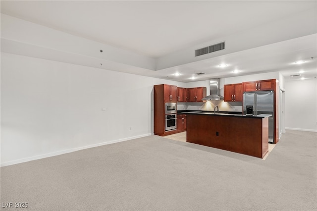 kitchen with visible vents, built in appliances, light carpet, dark countertops, and wall chimney range hood