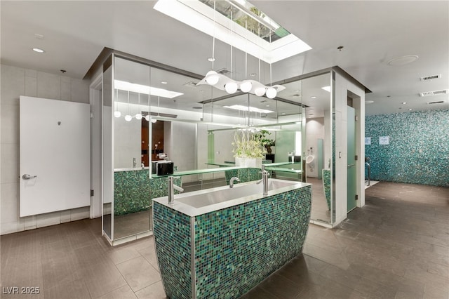 full bath featuring an inviting chandelier, a skylight, and visible vents