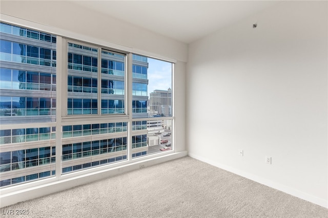 spare room featuring carpet flooring and baseboards