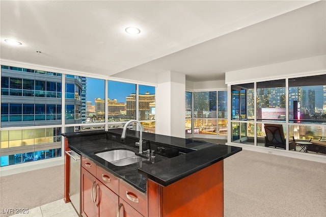 kitchen with a sink, light carpet, dark stone countertops, a view of city, and stainless steel dishwasher