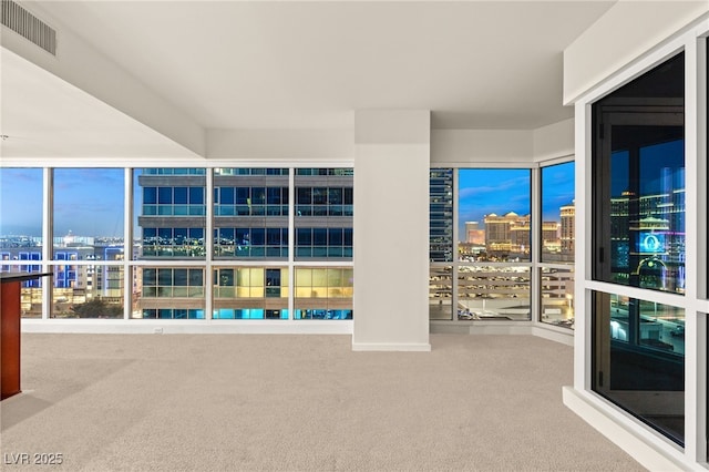 empty room featuring visible vents, a view of city, and carpet